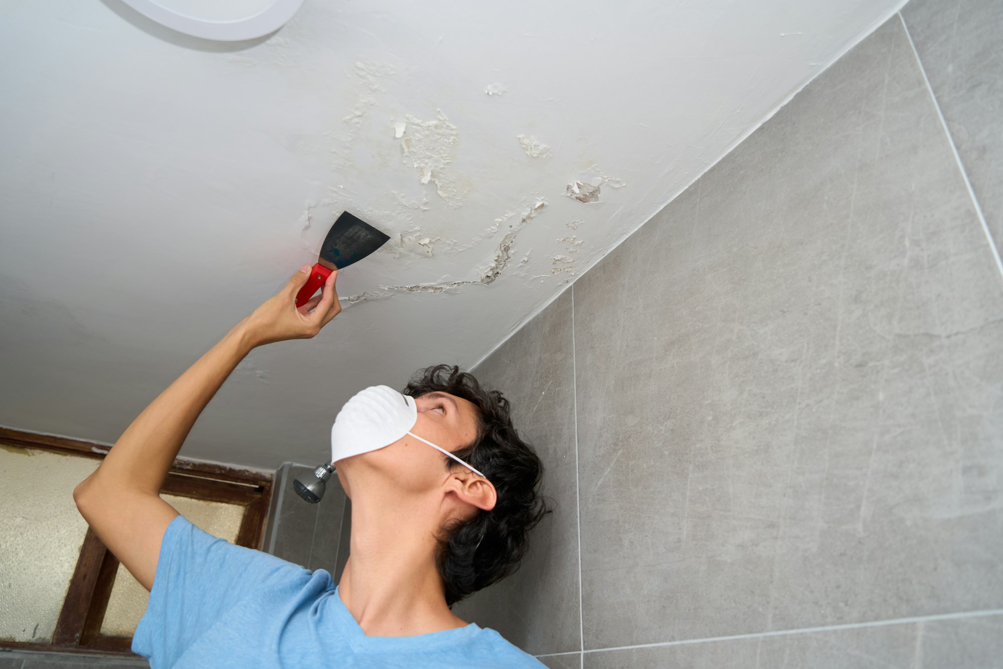 Young man fixing damp and saltpeter problem on the wall and ceiling