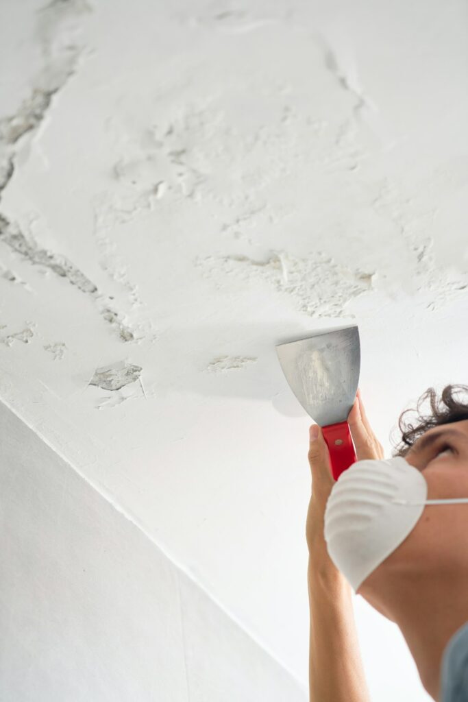 Young man fixing damp and saltpeter problem on the wall and ceiling